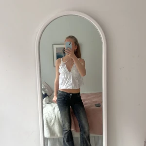 Vit linnetopp med volangdetaljer - Säljer en söt vit linnetopp med volangdetaljer och smala axelband. Toppen har en luftig passform och knytband vid axlarna för justering. Jag har knutigt den så den blir lite kortare då den annars är för urringad men kan enkelt ta bort. Perfekt för varma sommardagar!💓🌺