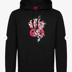 Svart hoodie från Hugo - Snygg svart hoodie från Hugo med en cool röd och vit grafisk design på framsidan. Den har en klassisk känguruficka och justerbar huva med dragsko. Perfekt för en avslappnad stil.