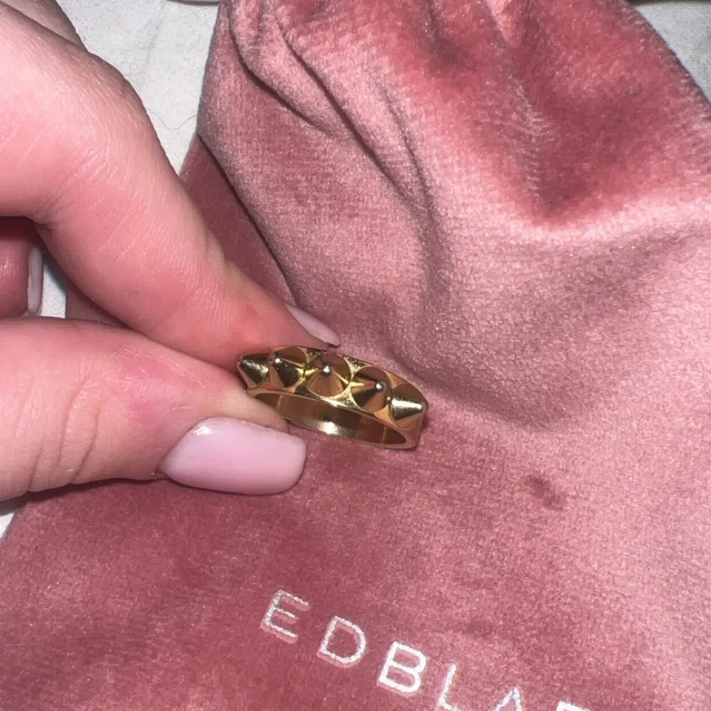 Snygg guldfärgad ring från Edblad med ett unikt pyramidmönster. Perfekt för att ge en edgy touch till din outfit. Kommer i en fin rosa påse.. Asusteet.