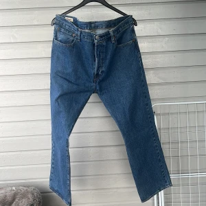 Levi's 501 Jeans - Klassiska blå Levi's 501 jeans med rak passform. Tillverkade i slitstarkt denim med fem fickor och knappgylf. Perfekta för en tidlös stil.