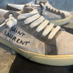 Saint laurent skor - SAINT LAURENT Destroyed Canvas Embroidered Womens Court Classic Sneakers. Nypris ca 7000kr!                                                        Sjukt snygga saint laurent sneakers! I väldigt bra skick, slitningarna fram är designen! Storlek 38(passar 39 också)