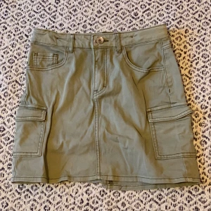 Grön cargo jeanskjol - Jätte snygg grön jeanskjol. I stretchig material och med band man kan spänna eller lossa. Storlek 152 barn, hade sagt att den är XS