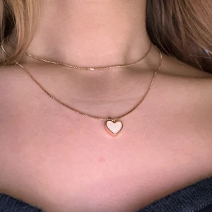 Guldhalsband med hjärthänge - Elegant guldhalsband med ett litet hjärthänge. Perfekt för att lägga till en subtil touch av kärlek och stil till din outfit. Justerbar kedja för perfekt passform. Ej rost fri.