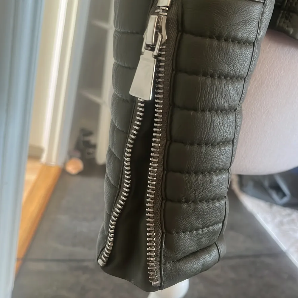 Snygg olivgrön skinnjacka med asymmetrisk dragkedja. Jackan har flera dragkedjor och spännen i midjan för en justerbar passform. Säljer pga att den tyvärr inte sitter bra på mig, lite avskad på insidan men inget som syns när man har på sig den 💚pris kan diskuteras. Takit.