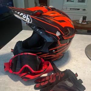 Mycket fint skick! Svart och röd hjälm från Airoh - Säljer en cool svart och röd hjälm från Airoh med matchande röd och svart mönstrad design. Hjälmen har en skärm och är perfekt för motocross eller moped. Inkluderar även ett par röda glasögon från oakley och svarta handskar från 100% i storlek M. Nypris för dessa 2200+600+369=3 169:- Använda under en knapp månad, så väldigt fint skick! Några mindre ytliga repor finns, aningen noppigt på insidan av hjälmen om man granskar noga, närbilder finns på allting och kan fås vid intresse. Skambud undanbes