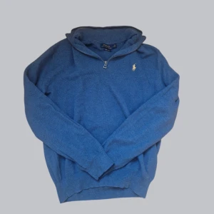 Blå tröja med dragkedja från Polo Ralph Lauren - Säljer en snygg blå tröja från Polo Ralph Lauren i mjuk pima bomull. Tröjan har en liten dragkedja vid halsen och det ikoniska logotypbroderiet på bröstet. Perfekt för en stilren look.