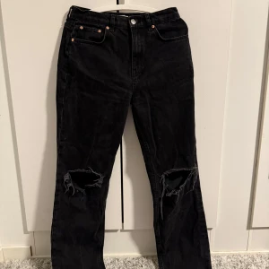 Svarta jeans med slitningar - Snygga svarta jeans från Perfect Jeans med slitningar på knäna. De har en klassisk femficksdesign och knappgylf. Perfekta för en avslappnad stil.
