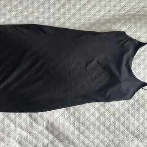 Svart axelbandslös klänning - Elegant kort svart klänning med smala axelband som formar kroppen superfint. Perfekt för en stilren look. Klänningen är tillverkad i ett mjukt och följsamt material. Knappt använd och väldigt bekväm🦋
