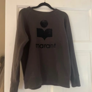 Grå sweatshirt från Isabel Marant - Säljer en grå sweatshirt från Isabel Marant med ett svart tryck på framsidan. Tröjan har långa ärmar och en rund halsringning. Perfekt för en avslappnad stil. Pris är inte hugget i sten💕💕💕