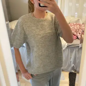 Säljer en stilren grå stickad tröja från Gina Tricot. Den har en normal passform med korta ärmar. Andvänd fåtals gånger och bra skick!