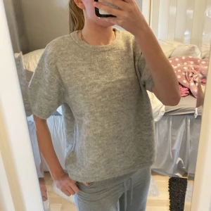 Grå tröja från Gina Tricot - Säljer en stilren grå stickad tröja från Gina Tricot. Den har en normal passform med korta ärmar. Andvänd fåtals gånger och bra skick!