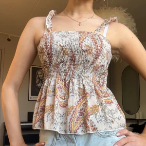 Mönstrad topp  - Säljer en söt topp med smockdetaljer och paisleymönster i rött, orange och beige. Toppen har  luftig passform som är perfekt för varma dagar. Hör av er vid frågor!!💞🌸