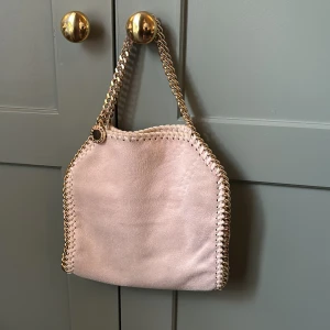 Ljusrosa Stella MCcartney! - Säljer min super fina Stella MCcartney väska! Den är ljusrosa och i jättebra skick. Den har jätte små fläckar typ som lite smuts men det går enklet att borsta bort. Kedjan har inga defekter och det samma med insidan av väskan. Skriv gärna till mig om ni vill se äktihetsbevis och andra frågor. Pris går att diskutera ❤️💕