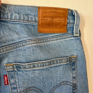 Levi's ljusblå jeans - Säljer ett par klassiska ljusblå Levi's jeans med hög midja och rak passform. De har den ikoniska läderpatchen baktill och en röd Levi's etikett på bakfickan. 