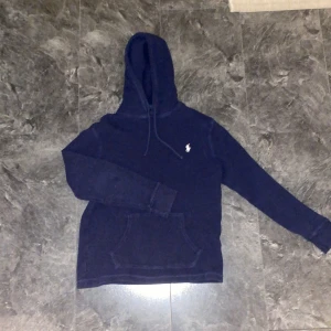 Mörkblå hoodie från Polo Ralph Lauren - Säljer en snygg mörkblå hoodie från Polo Ralph Lauren med ribbad struktur och klassisk logga på bröstet. Den är i gott skick. Tveka inte för minsta fråga