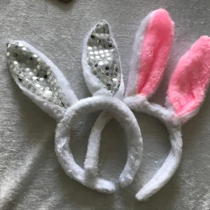 Diadem med kaninöron - Två fluffiga diadem med kaninöron. Ett par har vita och silverglittriga öron, medan det andra har vita och rosa öron. Perfekt för en rolig och lekfull look! Ny 