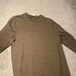 Brun tröja i merinoull - Säljer en stilren brun tröja i ull med rund hals och långa ärmar. Perfek och enkel att matcha med olika outfits. Tröjan har en klassisk design som passar till många tillfällen.