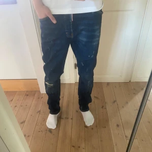 Blå jeans från Dsquared2 - Snygga blå jeans från Dsquared2 med en cool, sliten look och färgstänk. De har en klassisk femficksdesign och en bekväm passform. Perfekta för en avslappnad stil.