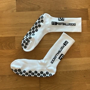 4 par helt nya vita fotbollsstrumpor med grepp  - Säljer 4 par helt nya vita fotbollsstrumpor med grepp på undersidan och svart logga på skaftet för bara 200kr. Perfekta för fotbollsträning, gym och springa. sitter bra på foten och ger extra grepp i skorna.