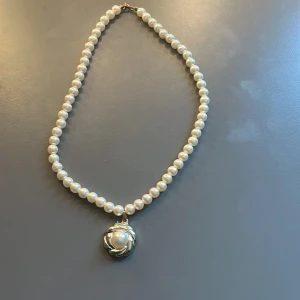 Klassiskt pärlhalsband med hänge - Handgjort halsband med vita pärlor och ett större runt hänge i silverfärg med en central pärla. 