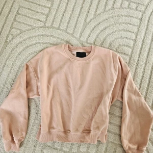 Ljusrosa sweatshirt - Säljer en ljusrosa sweatshirt med rund hals och långa ärmar. Tröjan har en avslappnad passform och är perfekt för en chill vardagslook. Mjuk och skön att ha på sig.