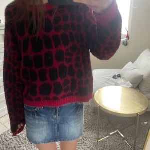 Röd och svart mönstrad stickad tröja - Säljer en cool stickad tröja i rött med svart leopardmönster. Tröjan har lång ärm och en lite loose passform. Perfekt att styla med jeans eller kjol. Köpt i Milano, bara använd en gång💗