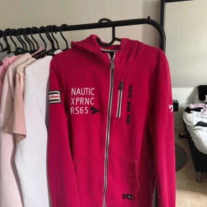 hoodie från Nautic XPRNC - hoodie med dragkedja från Nautic XPRNC. Jackan har huva, broderade detaljer och tryck på bröstet samt ärmen. Praktiska fickor framtill och sportig look med vita och svarta detaljer. Perfekt för en avslappnad stil.