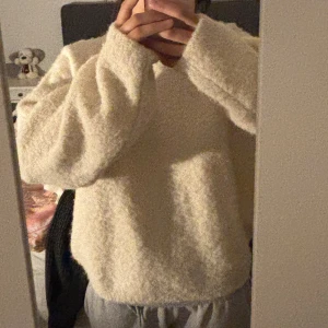 Vit fluffig stickad tröja - Mysig vit stickad tröja med fluffig textur och lång ärm. Perfekt för kyliga dagar och enkel att matcha med olika outfits. Avslappnad passform och rund halsringning.