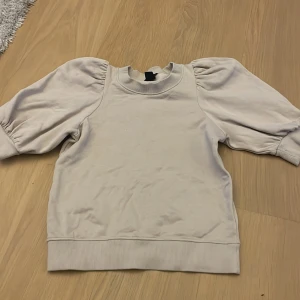 Beige sweatshirt med puffärm från Lindex - Säljer en beige sweatshirt från Lindex i storlek XS. Tröjan har puffiga långärmar och breda muddar vid ärmslut och nederkant. Perfekt för en avslappnad och trendig look. Jättegullig och stockholmstil! Skriv för bilder när jag har på mig den! Först till kvarn!