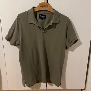 Olivgrön pikétröja från Bondelid - Säljer en stilren olivgrön pikétröja från Bondelid i storlek M. Tröjan har klassisk krage och korta ärmar.