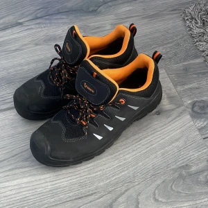 Svarta sneakers med orange detaljer från Vismo - Svarta sneakers med orange insida och detaljer, samt svarta och orangea snören. Skorna har platt sula och rund tå, samt reflekterande inslag på sidorna. Perfekta för dig som gillar sportig stil. Helt nya 