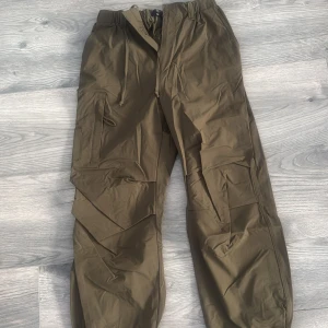 Olivgröna cargopants med fickor - Säljer ett par olivgröna cargopants med flera praktiska fickor på sidorna och justerbar midja. Byxorna har en loose passform och är perfekta för en avslappnad stil.