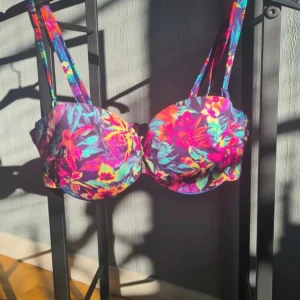 Bikiniöverdel 70B - Mycket fin bikiniöverdel med löstagbara band och insydda byglar. Så du får supporten man vill ha även fast du slipper solbrännan efter axelbanden. Den har även vadderade kupor och gummi sömm så den ska sitta på plats.  Guld detaljen mellan brösten går att ta bort om så önskas.  Den är använd några gånger men fortfarande mycket fint skick! Och tvättad i oparfymerat tvättmedel.  Storlek 70B, passar även A  Alla kläder rollas innan de skickas då katt finns i hemmet!🐈  #bikinitop #bikinibra #bikini 