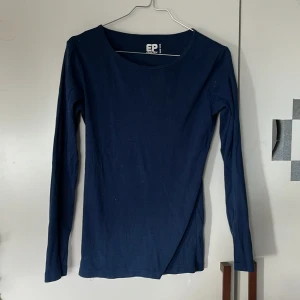 Mörkblå långärmad topp från EP Collection - Säljer en enkel och stilren mörkblå långärmad topp från EP Collection. Tröjan har rund halsringning och är tillverkad i mjuk bomull, perfekt för lager-på-lager eller som basplagg. Passar dig som gillar klassiska och tidlösa plagg.