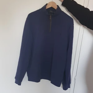 Marinblå halvsip från Polo Ralph Lauren - Säljer en marinblå långärmad tröja från Polo Ralph Lauren med halv dragkedja vid halsen. Klassisk och stilren modell som passar perfekt till många tillfällen. Mjuk och bekväm, med diskret logga på bröstet. Storlek XL men funkar för L också