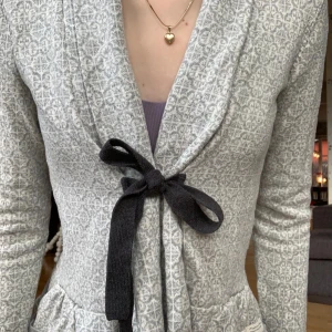 Grå mönstrad cardigan från Odd Molly  - Grå cardigan kofta från Odd Molly med ljusgrått mönster och svart knytband i midjan. Koftan har volangdetaljer nedtill och lång ärm. Perfekt för lager-på-lager och snygg till både jeans och klänning. Skulle säga att storlek 1 Odd Molly motsvara ungefär xxs-xs eller ca 158