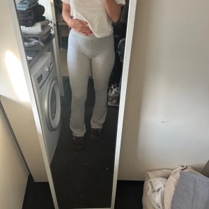 Grå mjukisbyxor med hög midja - Säljer ett par ljusgrå mjukisbyxor med hög midja. Byxorna är tighta och har en enkel, klassisk design utan synliga detaljer. Perfekta för en avslappnad stil.