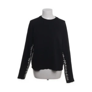 Svart långärmad tröja från Carin Wester - Svart långärmad tröja från Carin Wester med vit textdetalj längs ärmarna. Enkel och stilren design med rund halsringning. .