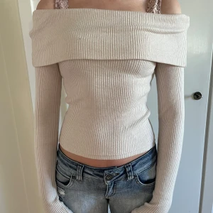 Beige ribbad offshouldertröja från Gina Tricot - Säljer en beige ribbad offshouldertröja från Gina Tricot. Tröjan har långa ärmar och en bred, vikt kant över axlarna. Materialet är mjukt och stretchigt, perfekt för en trendig och stilren look. Köpte varan för 399kr