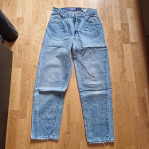 Levi's SilverTab Baggy jeans - Säljer ett par klassiska ljusblå Levi's SilverTab Baggy jeans med bred passform och raka ben. Jeansen har fem fickor, bälteshällor och en snygg vintage look. Perfekta för dig som gillar avslappnad stil.