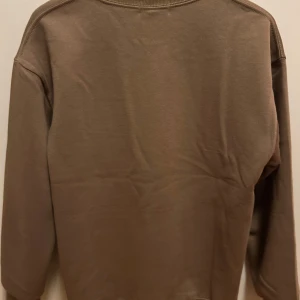 Beige sweatshirt från Polo Ralph Lauren - Säljer en stilren beige sweatshirt från Polo Ralph Lauren med klassisk rund halsringning och broderad logga på bröstet. Perfekt för en avslappnad och snygg look.
