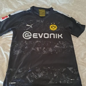 Borussia Dortmund tröja - Säljer en svart Borussia Dortmund bortatröja från Puma med tryck 'Sancho 7' på ryggen. Aldrig använd, fick den som present från släktingar i USA men den va tyvärr för liten (Storlek S)