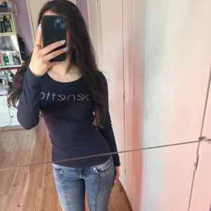 Mörkblå långärmad topp från United Colors of Benetton - Säljer en mörkblå långärmad topp från United Colors of Benetton med rund halsringning och tight passform. Perfekt till jeans och enkel att styla. Diskret logga framtill.