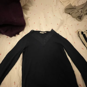 Mörk blå långärmad topp med spets Gina Tricot - Supersnygg mörk blå långärmad topp från Gina Tricot med v-ringning och dekorativ spets runt halsen. Perfekt för dig som gillar en stilren look med lite extra detalj. Mjuk och skön, passar till många outfits.