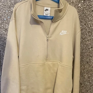  half zip hoodie från Nike  - Snygg beige hoodie från Nike i storlek XS med half zip och hög krage. Tröjan har lång ärm, stor ficka framtill och broderad Nike-logga på bröstet.