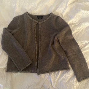 Grå kofta i ull och kashmir från Massimo Dutti - Supermjuk grå kofta från Massimo Dutti i ull och kashmir. Enkel och stilren modell med rund halsringning, lång ärm och diskret ribbad kant. Perfekt att slänga över ett linne eller t-shirt. Man kan ha den till vardags bara för att få outfiten lite extra snygg. 