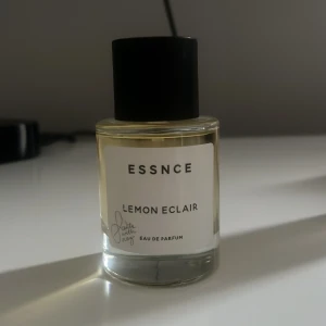 ESSNCE Lemon Eclair parfym - Fräsch parfym från ESSNCE med doften Lemon Eclair. Kommer i en stilren, genomskinlig glasflaska med svart lock och vit etikett. Eau de Parfum som ger en citrusig och söt vibe, perfekt för dig som gillar unika dofter. Helt oanvänd!!!