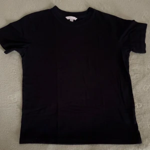 Svart t-shirt  - T-shirten har rund halsringning och korta ärmar, perfekt för en clean och enkel stil. Tillverkad i mjuk bomull som känns skön mot huden. Passar till allt och är ett måste i garderoben.