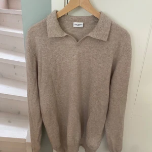Beige kashmirtröja från John Henric - Supermjuk beige långärmad tröja från John Henric i kashmir. Klassisk pikékrage och relaxed fit, perfekt för dig som gillar stilren och enkel design. Passar till jeans eller chinos för en clean look.