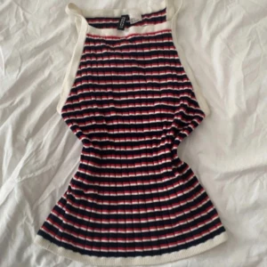 Randig ribbat linne från H&M - Superfin kort ribbat linne från H&M i marinblått, rött och vitt. Linnet har smala axelband, figurnära passform och är ärmlös. Perfekt för varma dagar.